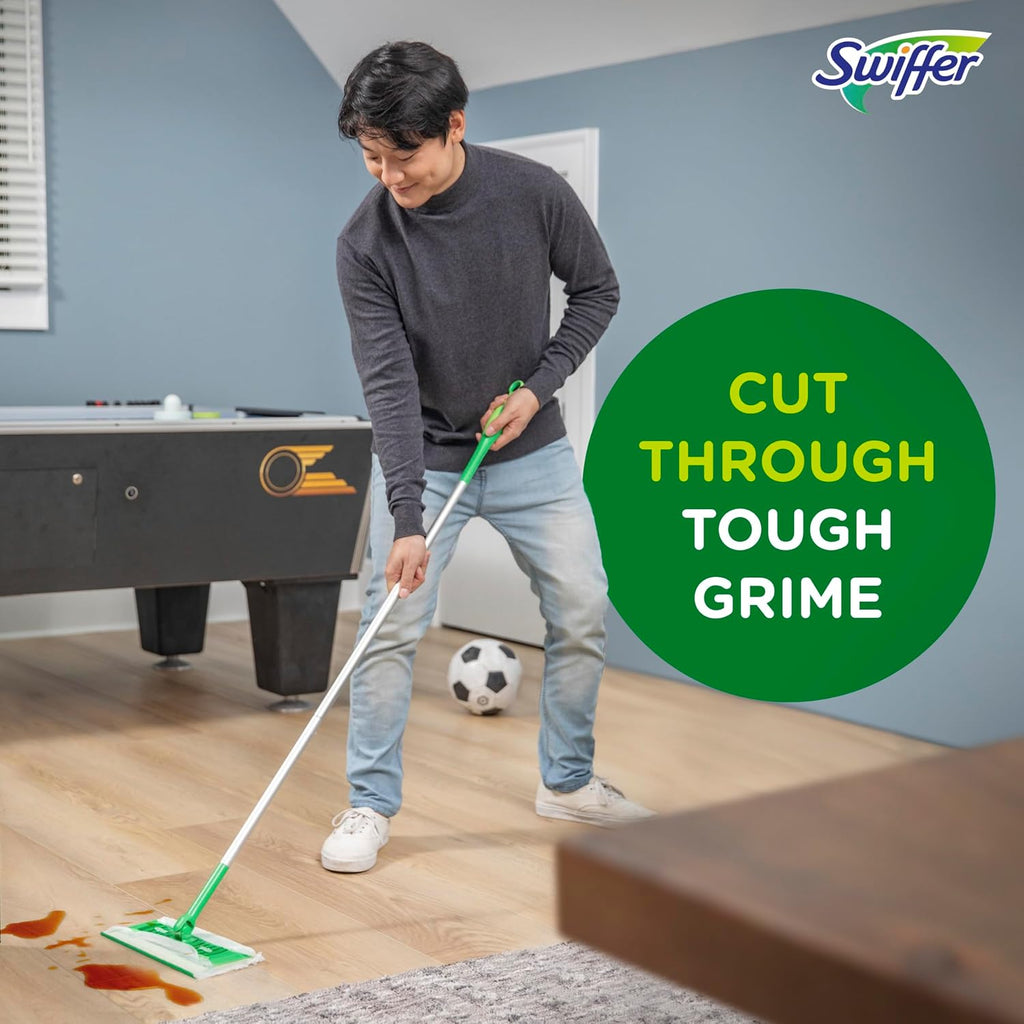 Person cleaning a wooden floor with a Swiffer sweep and mop, with a pool table and sports ball in the background.
