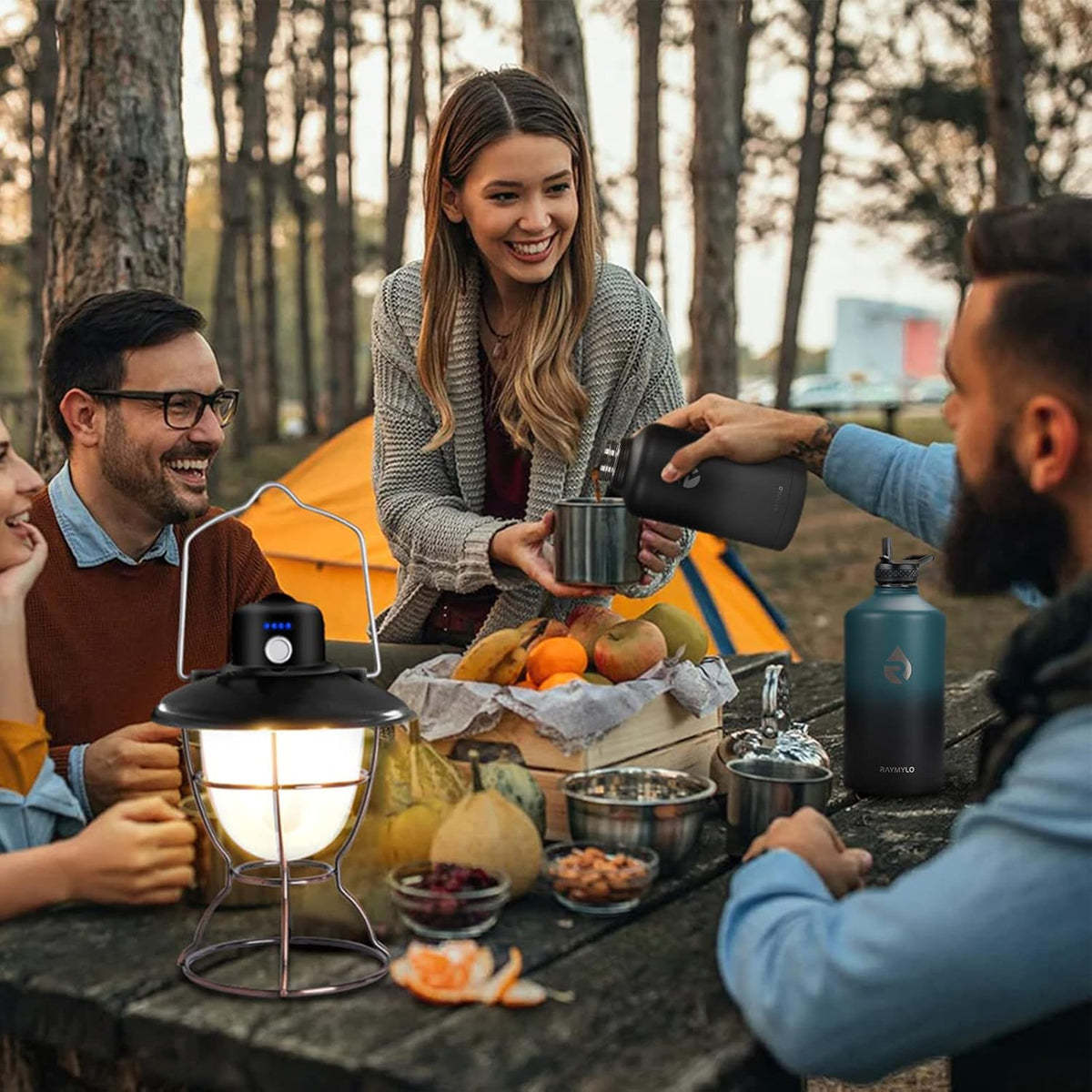 Group of people camping outdoors, using a portable lamp and enjoying snacks.