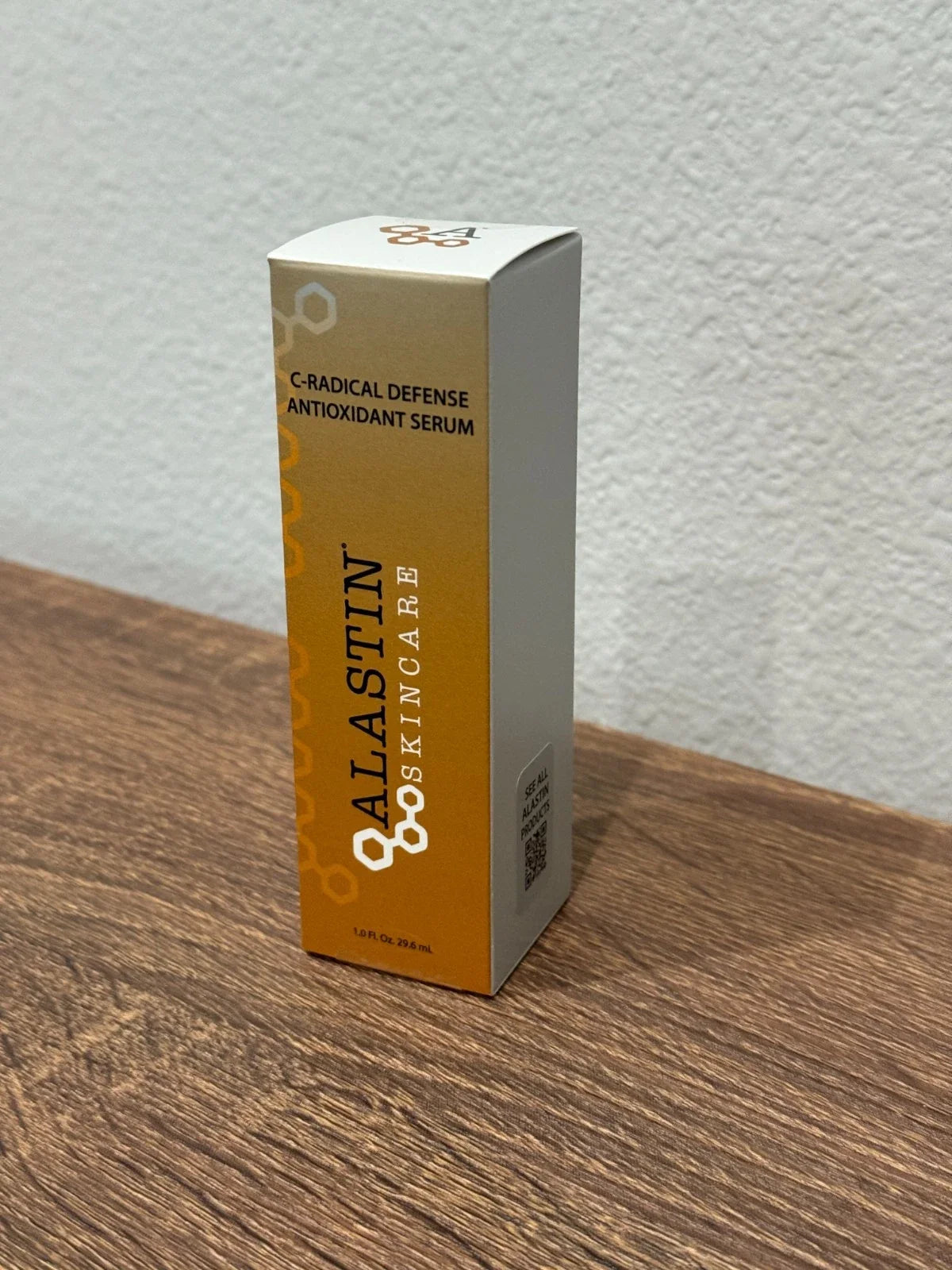 A box of Calastin Skincare C-Radical Defense Antioxidant Serum standing on a wooden surface against a textured white wall.