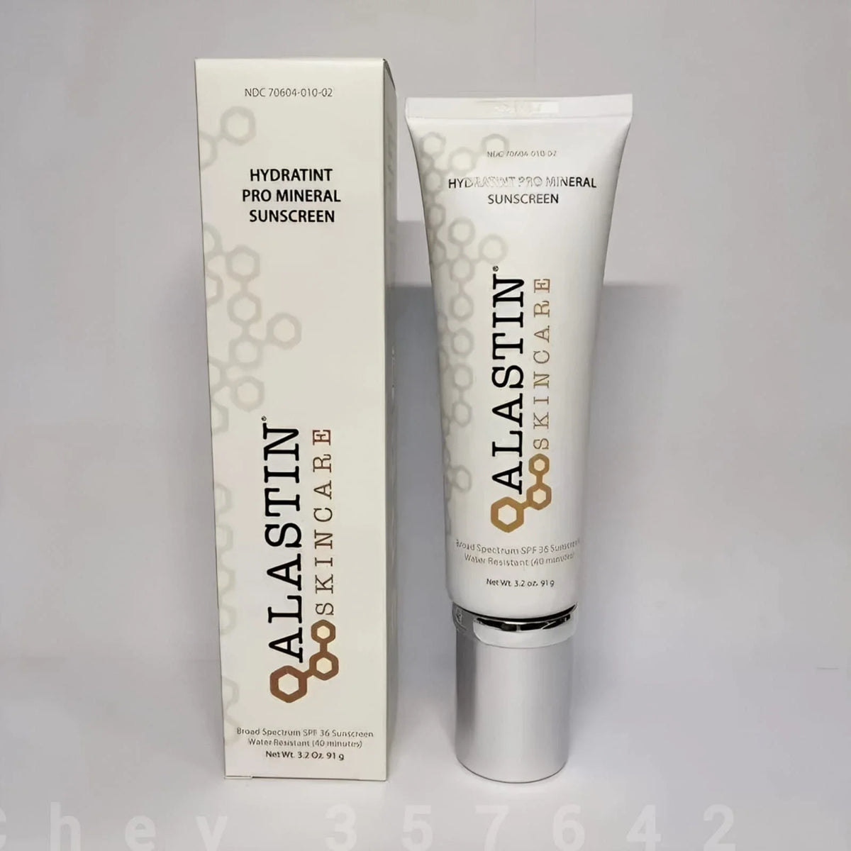 ALASTIN SKINCARE Hydratint Pro Mineral Sunscreen shown as a white squeeze tube with a silver cap next to its matching white packaging box on a light gray background.