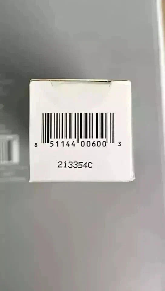A small white square box with a barcode and printed numbers, photographed against a gray background.