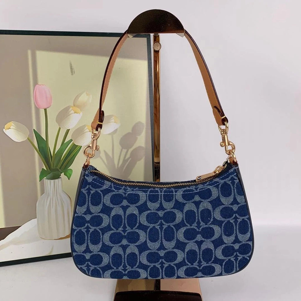 Blue handbag with gold accents on a white surface with a blurred background