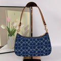 Blue handbag with gold accents on a white surface with a blurred background