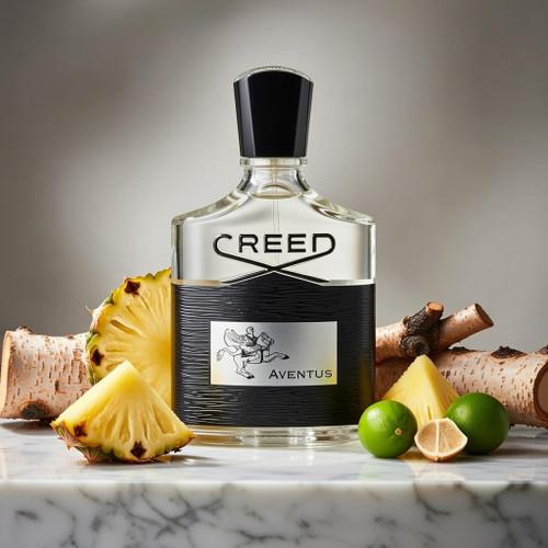 A bottle of Creed Aventus perfume centered on a marble surface, surrounded by pineapple slices, limes, wood bark, and cheese wedges against a soft gray studio background. The bottle label clearly shows the Creed brand and Aventus name.