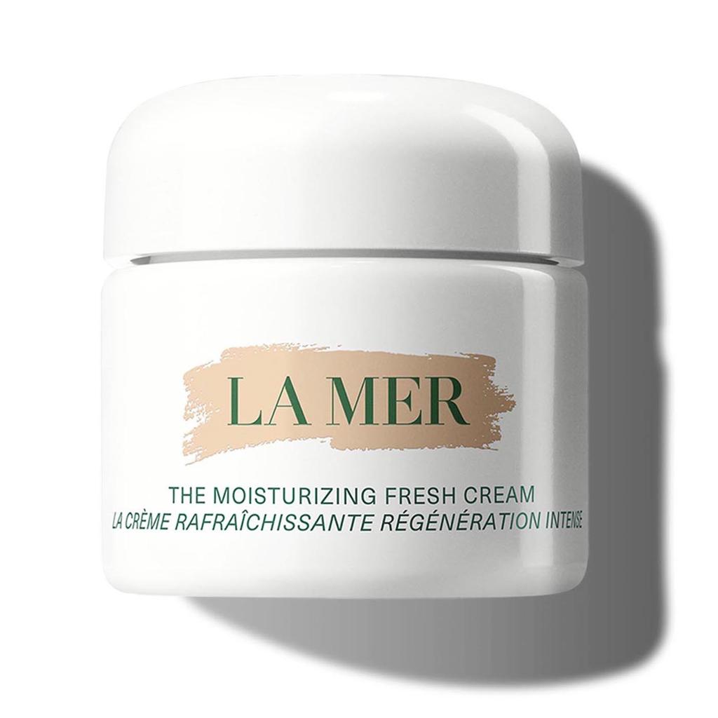 A white cosmetic jar of La Mer The Moisturizing Fresh Cream with a beige brushstroke logo and green lettering, set against a white background with a soft shadow.