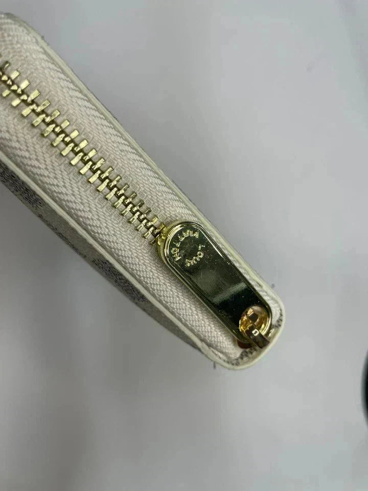 Close-up of a beige wallet with a gold zipper on a light gray background