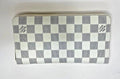 Louis Vuitton zip-around wallet in the Damier Azur checkerboard pattern, featuring alternating white and light gray textured squares with black brand logos on the sides.