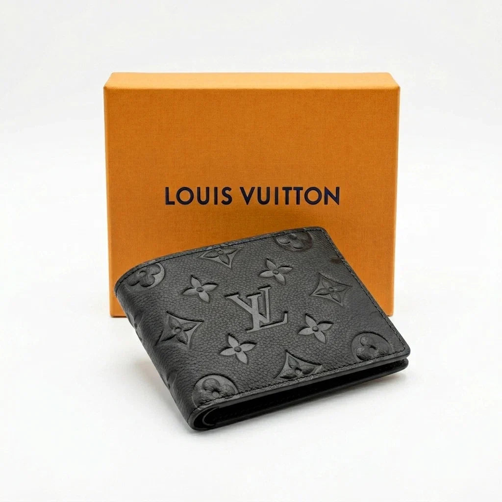 A black Louis Vuitton bi-fold wallet with the embossed monogram pattern, displayed in front of its signature orange brand box on a clean white background.