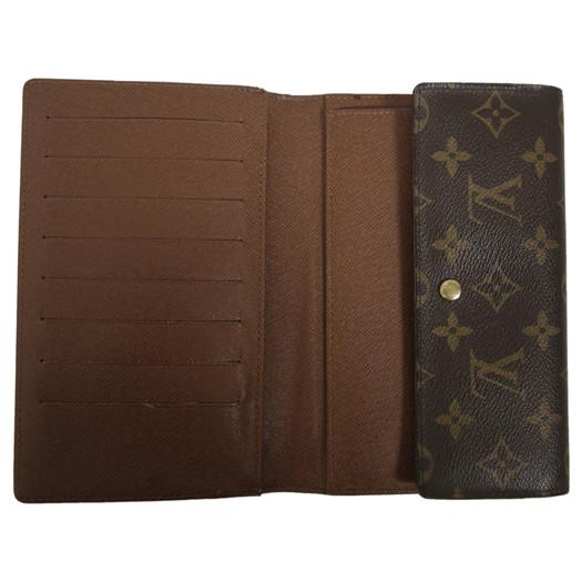 An open brown leather wallet or bifold with multiple card slots on the left and a monogram-patterned flap on the right, photographed on a plain white background.
