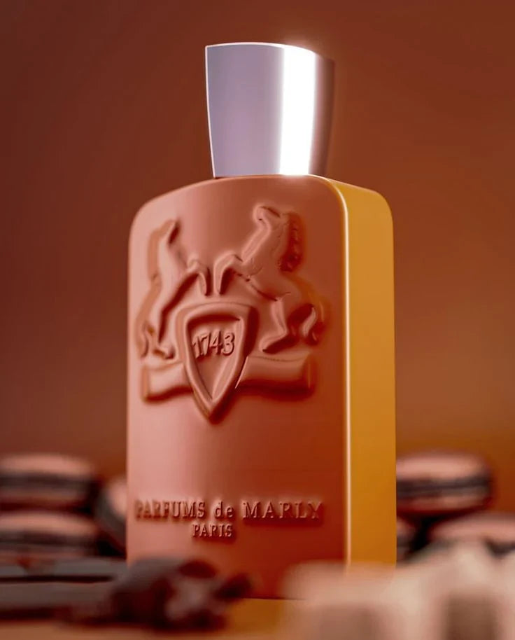 Perfume bottle with decorative emblem and 'Parfums de Marly' branding on a blurred background.