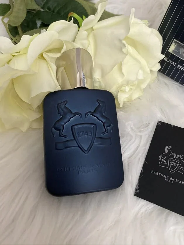Blue perfume bottle with packaging and flowers on a textured surface