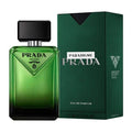 Prada Paradigme Milano Eau de Parfum bottle in green glass next to its textured dark green packaging box on a white background.