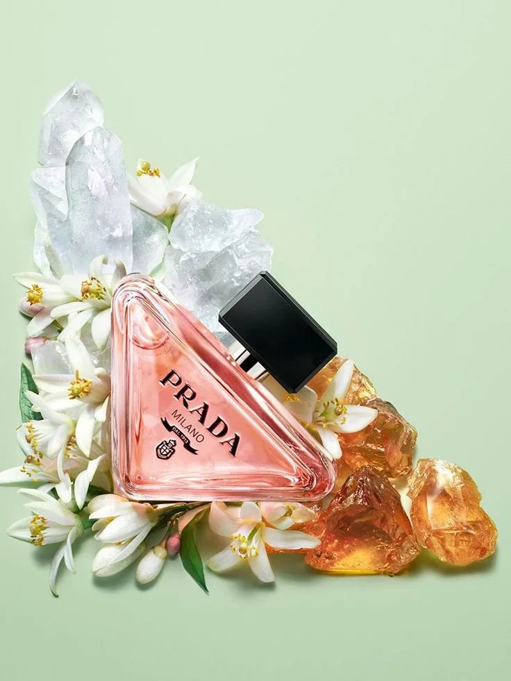 Prada perfume bottle with flowers and amber on a light green background