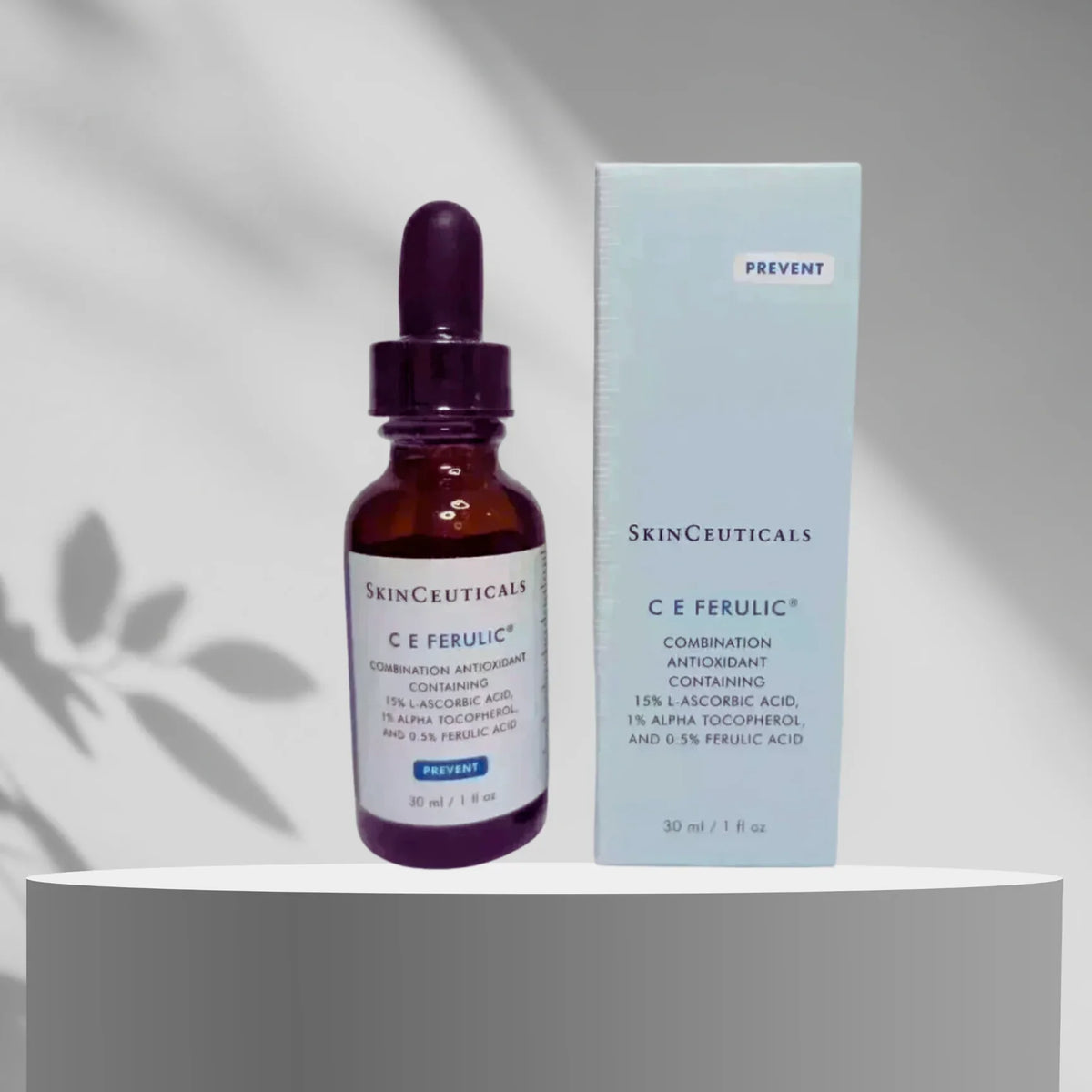 SkinCeuticals C E Ferulic combination antioxidant containing dropper bottle in an amber glass bottle with a dark purple dropper cap, standing next to its light blue cardboard packaging box on a white pedestal.