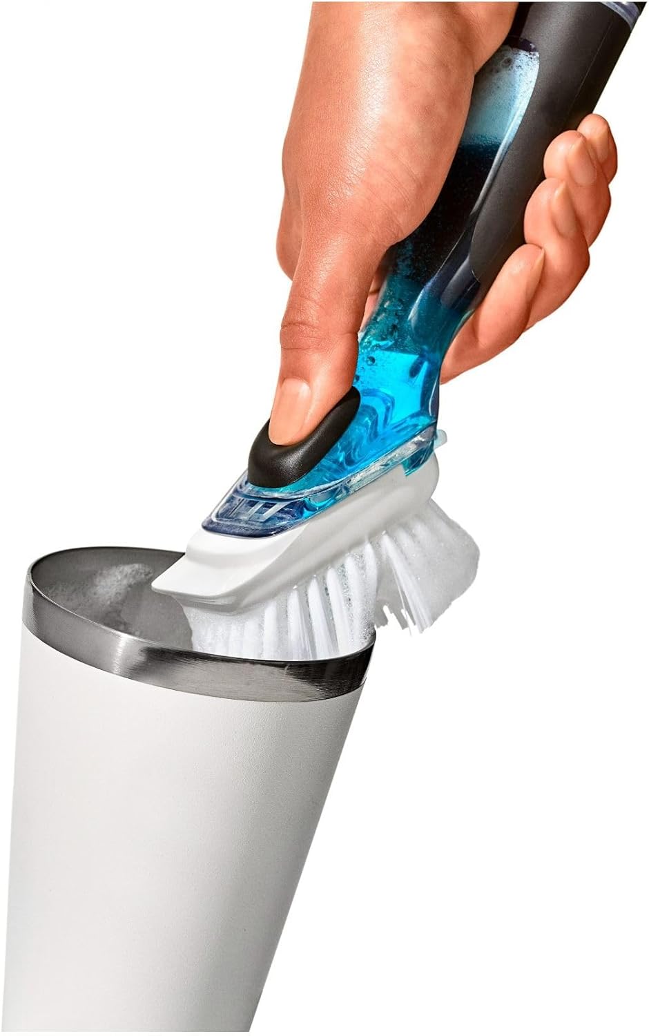 A hand holding a blue and black handheld cleaning brush above a white cylindrical container with a metal rim, shown against a plain white background.