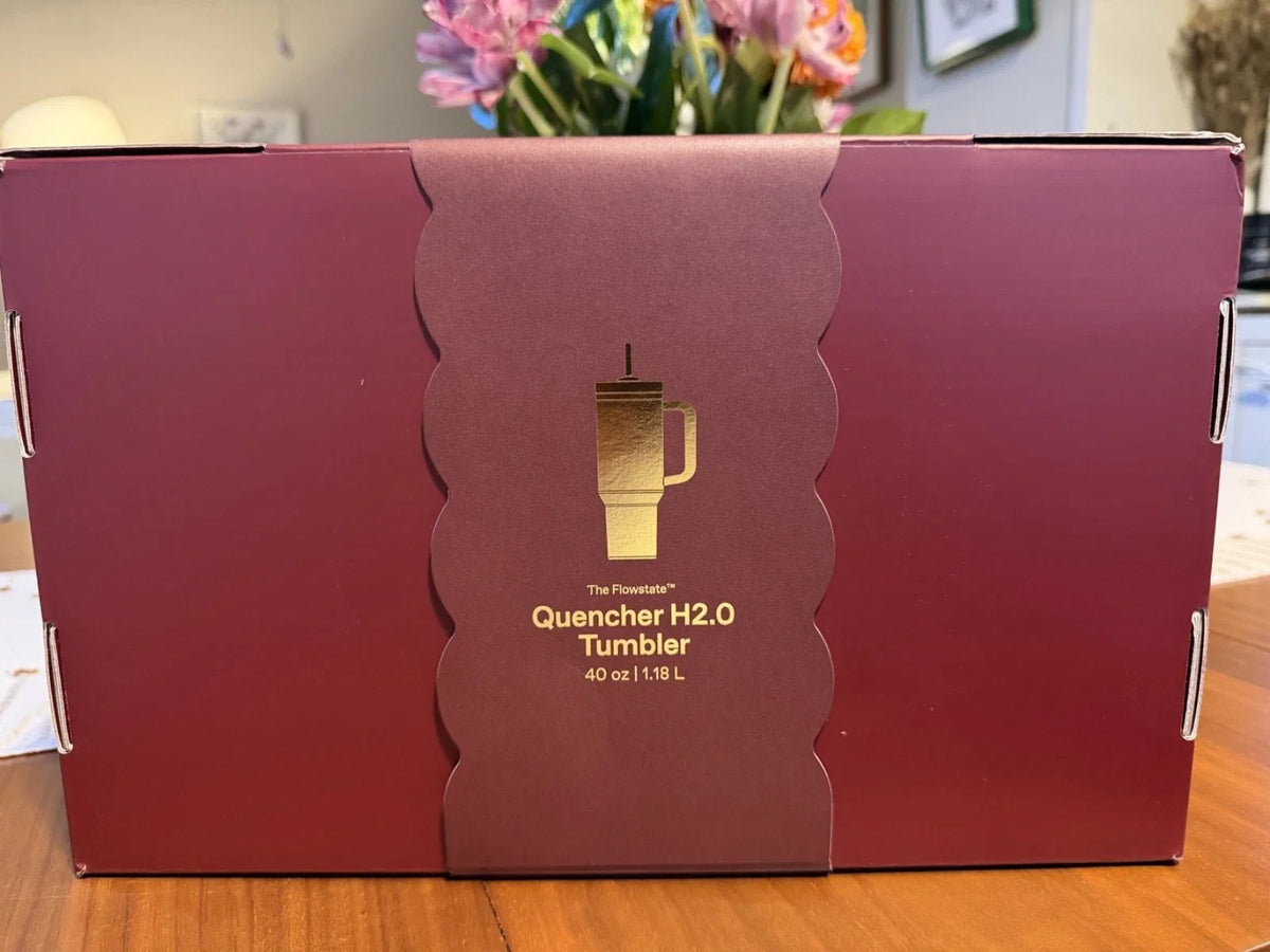 A dark red cardboard box with a scalloped center panel featuring a gold tumbler illustration and the text 'The Flawless Quencher H2.0 Tumbler 40 oz 1.