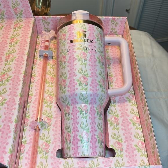 A pink floral Stanley tumbler with a handle and lid, displayed inside its matching pink floral gift box next to a matching straw.
