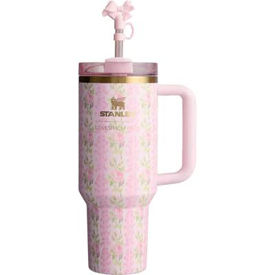 A pink Stanley tumbler with a floral pattern, featuring a built-in handle, a pink lid, and a matching pink straw with a bow on a white background.