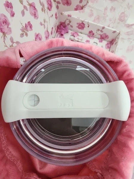 Stainless steel tumbler with a white lid on a pink floral background