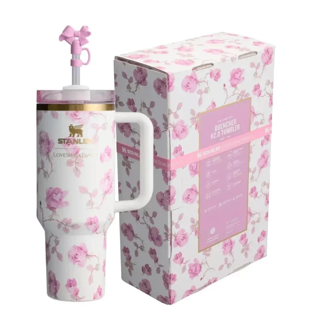 A pink and white floral patterned stainless steel travel mug with a handle and straw, shown next to its matching retail box. The packaging features a matching floral design with a pink label.