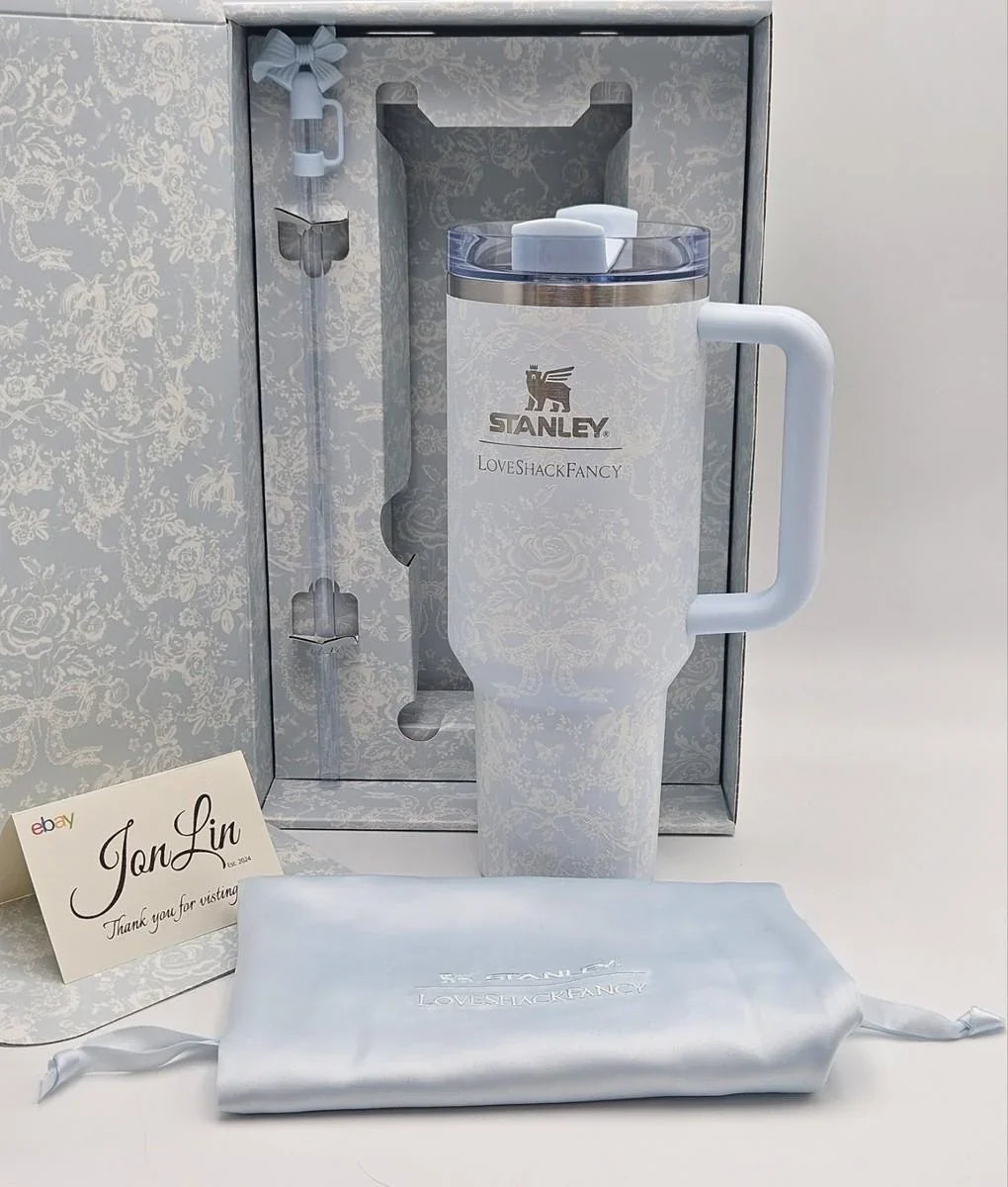 A Stanley LifetimeFangery insulated tumbler in a pale icy blue color, shown with its matching gift box, a light blue drawstring pouch, and a JonLin thank you card on a white background.